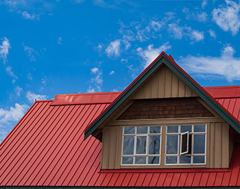 Close-up of a residential roof with a brand new red metal roof installed